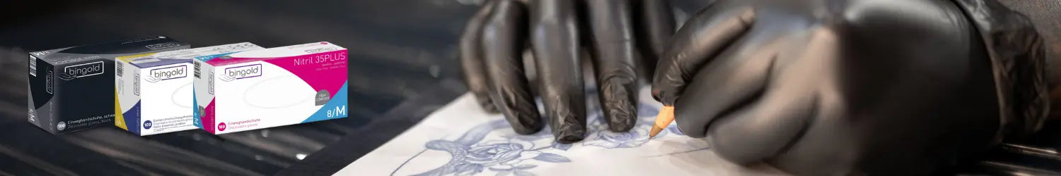 Der Banner zeigt eine Hand, die mit schwarzen Tätowierhandschuhen eine Rose auf Papier skizziert. Im Vordergrund sind drei verschiedene Packungen Einweghandschuhe der Marke Bingold zu sehen: eine schwarze, eine rosa und eine weiße Box, die jeweils unterschiedliche Varianten von Nitrilhandschuhen repräsentieren.