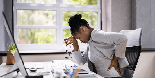 Frau am Schreibtisch mit Rückenschmerzen