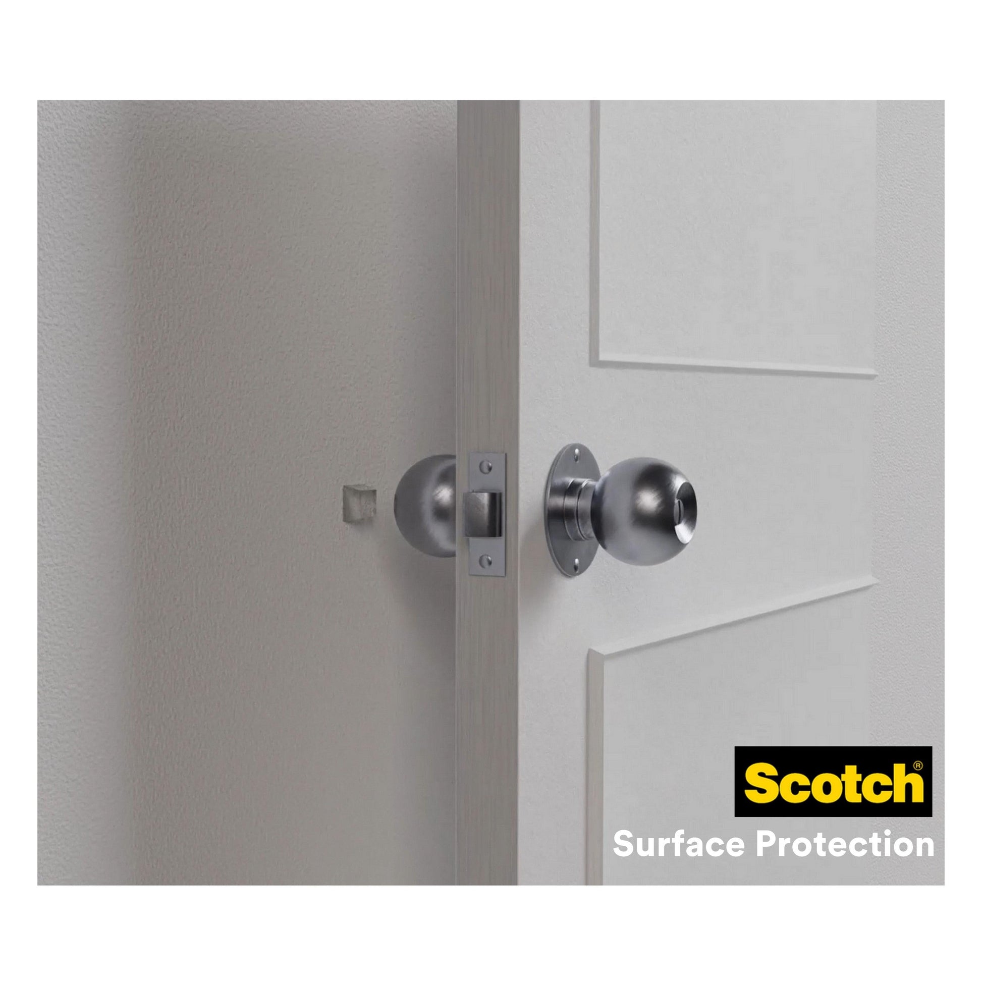 Ein silberner Türknauf an einer weißen Tür berührt fast eine Wand, an der zum Schutz ein transparenter Scotch® Stoßabsorbierende Elastikpuffer für Wände SP91A62 (21 mm x 21 mm, 6/Packung) von 3M Deutschland GmbH angebracht ist.