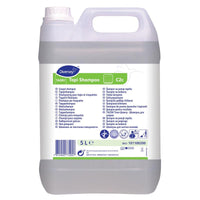 Un bidon de 5 litres de TASKI Tapi Shampoo de Diversey Deutschland GmbH & Co. OHG : shampoing neutre pour moquettes, certifié « Wollsiegel » et doté de la technologie O.N.T. pour une fraîcheur durable, avec une étiquette blanche, une poignée et un bouchon à vis.