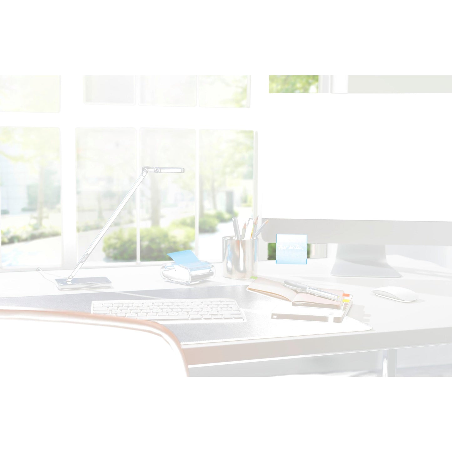 Eine moderne Schreibtischeinrichtung mit einem 3M Post-it® Z-Notes Dispenser PRO in Schwarz mit gelben Post-it® Super Sticky Z-Notes (76x76 mm, 90 Blatt/Block), Notizbüchern, Stiften und einer Lampe vor großen Fenstern mit Sonnenlicht und grünen Bäumen draußen.