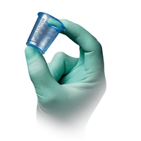 Une main gantée de vert clair tient l'un des gobelets médicaux AMPri PP de 30 ml, gradués en bleu transparent, fabriqués par la société AMPri Handelsgesellschaft mbH, avec une graduation en millilitres sur fond blanc.