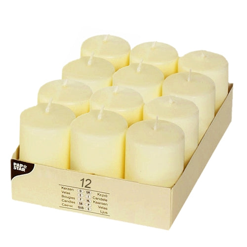 A box of 12 PAPSTAR pillar candles, Ø 40 mm, 60 mm high, ivory color, flat-top design by PAPSTAR GmbH. The cream-colored pillar candles are arranged in a cardboard tray; the box contains a label with the candle details.