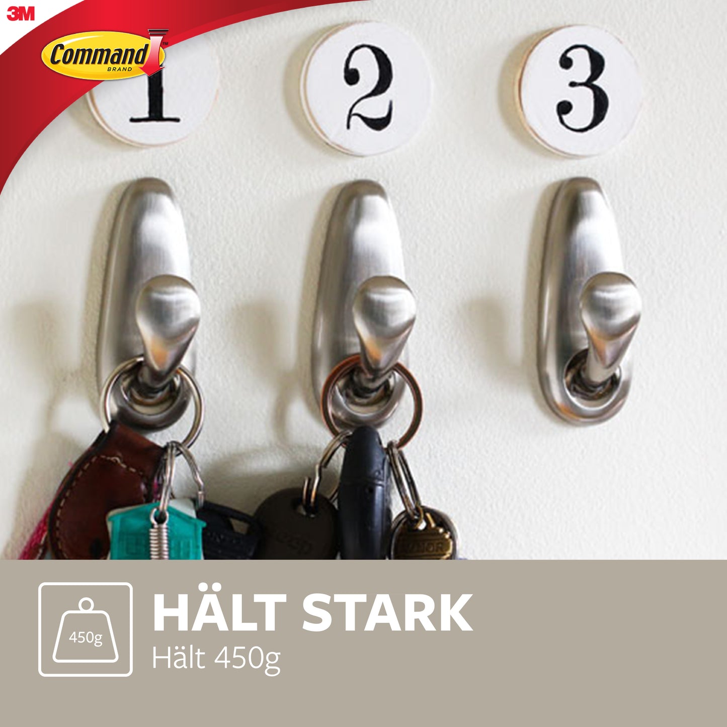 Drei Command™ Metallhaken "klassisch" von 3M Deutschland GmbH sind in einer Reihe montiert, nummeriert von 1 bis 3, und halten jeweils einen Schlüsselsatz. Oben links ist das Logo und der Text zu sehen: "HÄLT STARK, hält 450g.