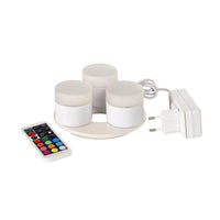 The Duni GmbH Mini Multicolour LED Set includes three small, round LEDs with a charging station, a white power adapter, and a remote control for selecting different colors and functions—perfect for creative lighting.