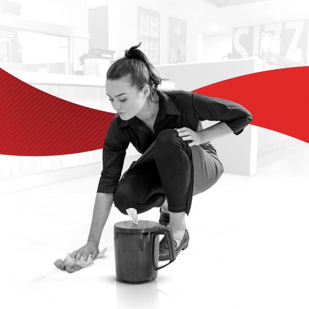 A woman in dark clothing cleans the floor with a WypAll® Reach™ paper towel from Kimberly-Clark GmbH. In front of her is a bucket with accessories. The scene against a white and red background shows the cleaning of service and sales areas.