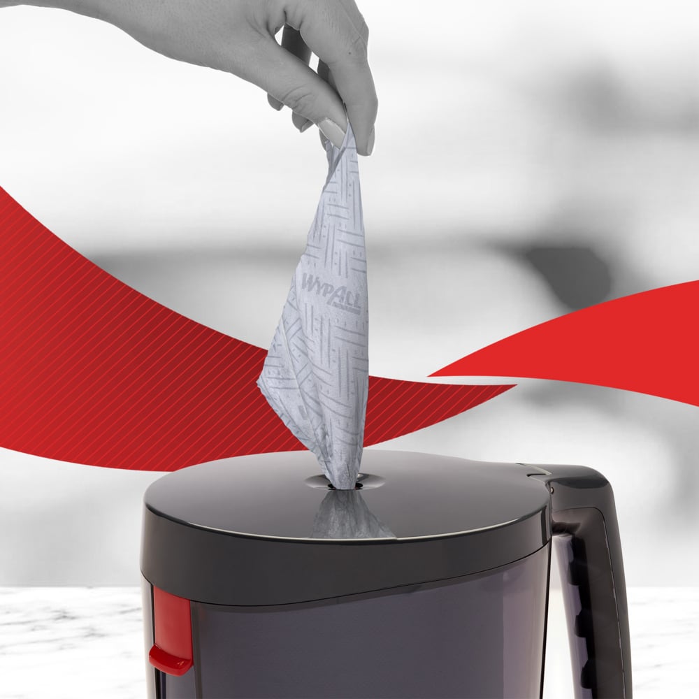 A hand pulls a WypAll® Reach™ blue paper towel for cleaning in service & retail from the central dispensing of a gray dispenser - ideal for professional cleaning services. Brand: Kimberly-Clark GmbH, 6 rolls of 280 sheets.