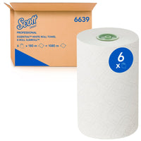 A large white Scott® Essential™ E-roll Slimroll™ is sitting in front of an open cardboard box from Kimberly-Clark GmbH. A blue sticker on the roll reads "6x." The single-ply roll towels are available in 6x180m packs.