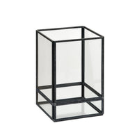 La lanterne Capella en verre noir de Duni GmbH est une lanterne rectangulaire dotée de bords métalliques noirs et d'une partie supérieure ouverte, qui offre un éclairage élégant sur un fond blanc sobre.