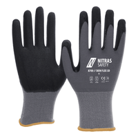 A pair of gray NITRAS SKIN FLEX knit gloves from AS Arbeitsschutz GmbH, featuring a special stretch knit and a partial black coating, displayed flat to show off their ergonomic fit and coated fingers.