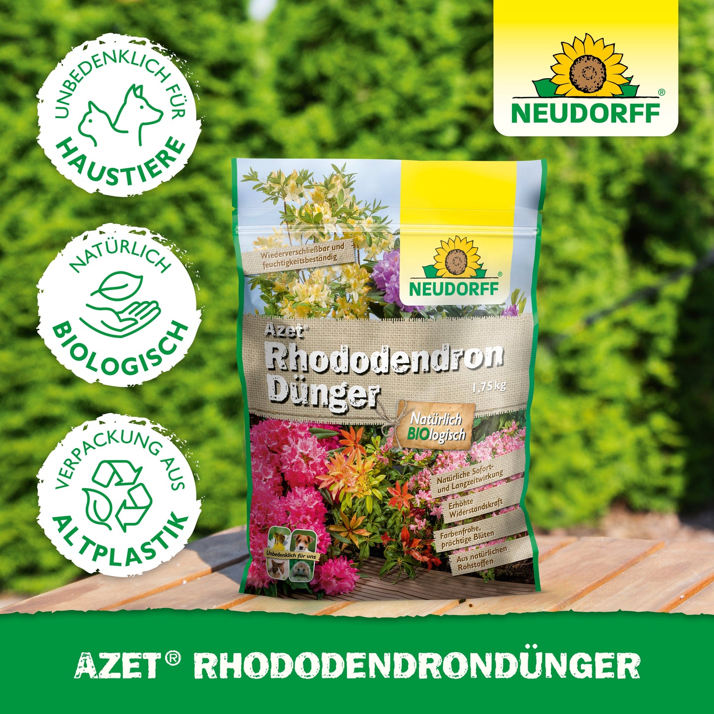Ein Beutel Azet RhododendronDünger aus dem Neudorff Shop liegt auf einer Holzfläche im Freien vor grünen Hecken. Auf der Verpackung aus Biokunststoff steht, dass er biologisch, haustierfreundlich und ideal für Rhododendren und Azaleen ist.