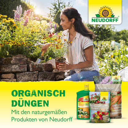 Eine Frau kniet in einem Garten und pflanzt in einem Hochbeet aus Stein. Abgebildet sind die Azet Düngestöcke für Zitrus- & Mediterranpflanzen von Neudorff Shop, perfekt für die biologische Pflege von mediterranen Kübelpflanzen auf Balkon und Terrasse.