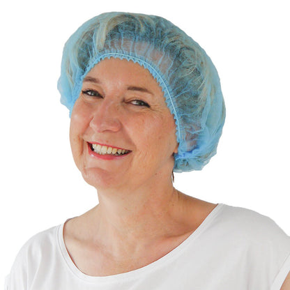 A woman smiles in front of a white background and wears an ARNOMED COVER PP-CLIP CAP XL disposable clip cap made of PP fleece (55cm circumference) from ARNOWA GmbH and a white shirt - ideal for maintaining hygiene standards.