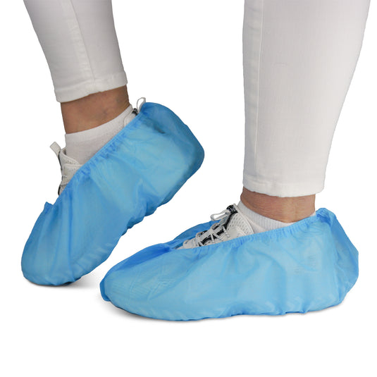 Eine Person trägt weiße Hosen und Sneaker mit ARNOMED ABS Schuhüberziehern von ARNOWA GmbH. Die rutschfesten Einweg-Überzieher (Beutel à 100 Stück) schützen Schuhe und Böden - ideal für hygienische Umgebungen.