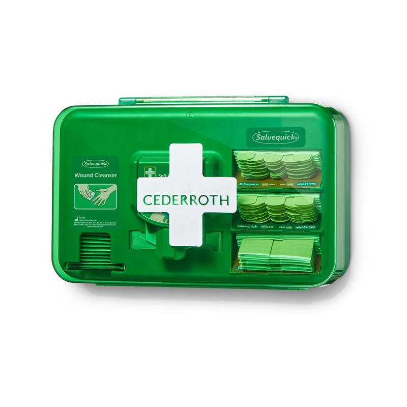 Abgebildet ist ein grüner Orkla Wound Care AB Cederroth Wound Care Dispenser (20,3x30,6x15,5 cm) mit einem weißen Kreuz, der durch die durchsichtige Kunststofffront sichtbare Verbrauchsmaterialien wie Bandagen und Reinigungsmittel enthält und als Folienbeutel-Set geliefert wird.