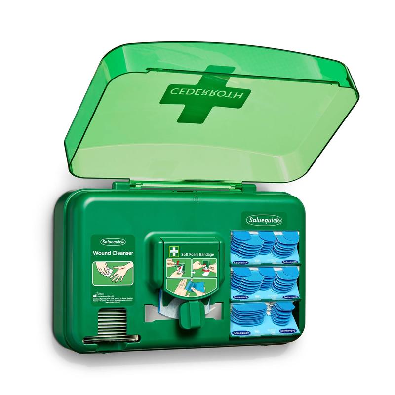 A blue wound care dispenser from Orkla Wound Care AB is open, revealing wound cleansing packets, plasters, and a roll of soft foam bandages arranged in individual compartments.