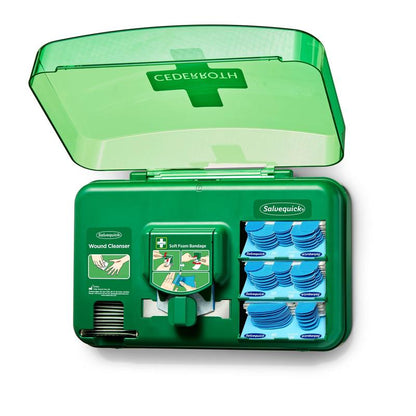 An open blue plastic wound care dispenser from Orkla Wound Care AB contains wound cleansing packets, soft foam dressings, and a dispenser. The transparent lid features a medical cross symbol. Sold as 1 pack in a box.