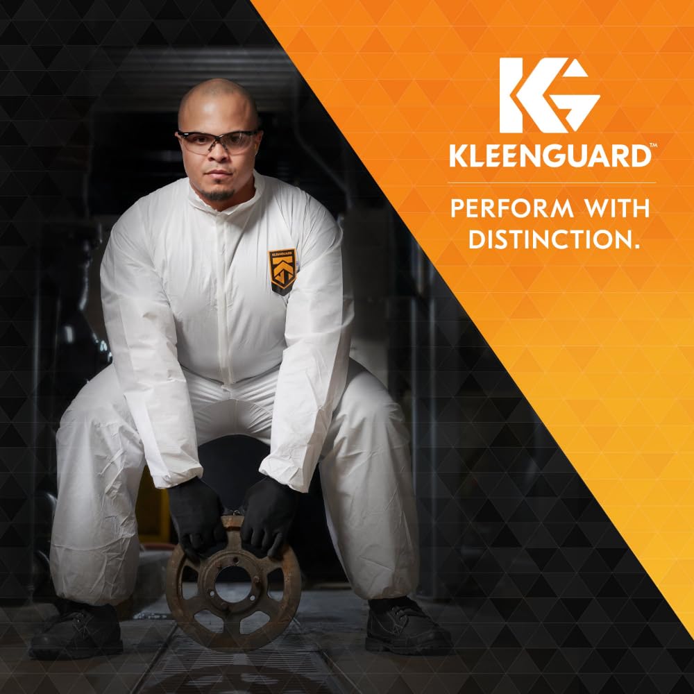 Eine Person in einem weißen Schutzanzug mit Logo, schwarzen Handschuhen und KleenGuard® V30 Nemesis™ Schutzbrille von Kimberly-Clark GmbH hält in der Hocke ein Metallrad. Das Bild zeigt das KleenGuard-Logo und "PERFORM WITH DISTINCTION" auf Orange.