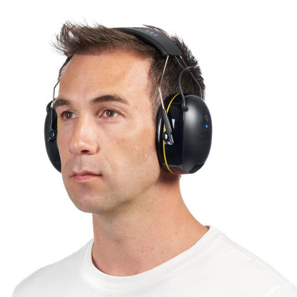 A man with short brown hair wears the 3M™ WorkTunes™ Connect Hearing Protector 90543E (SNR 31 dB, Bluetooth®, Black) from 3M Deutschland GmbH and a white crew neck shirt, looking slightly to the left with a neutral expression.