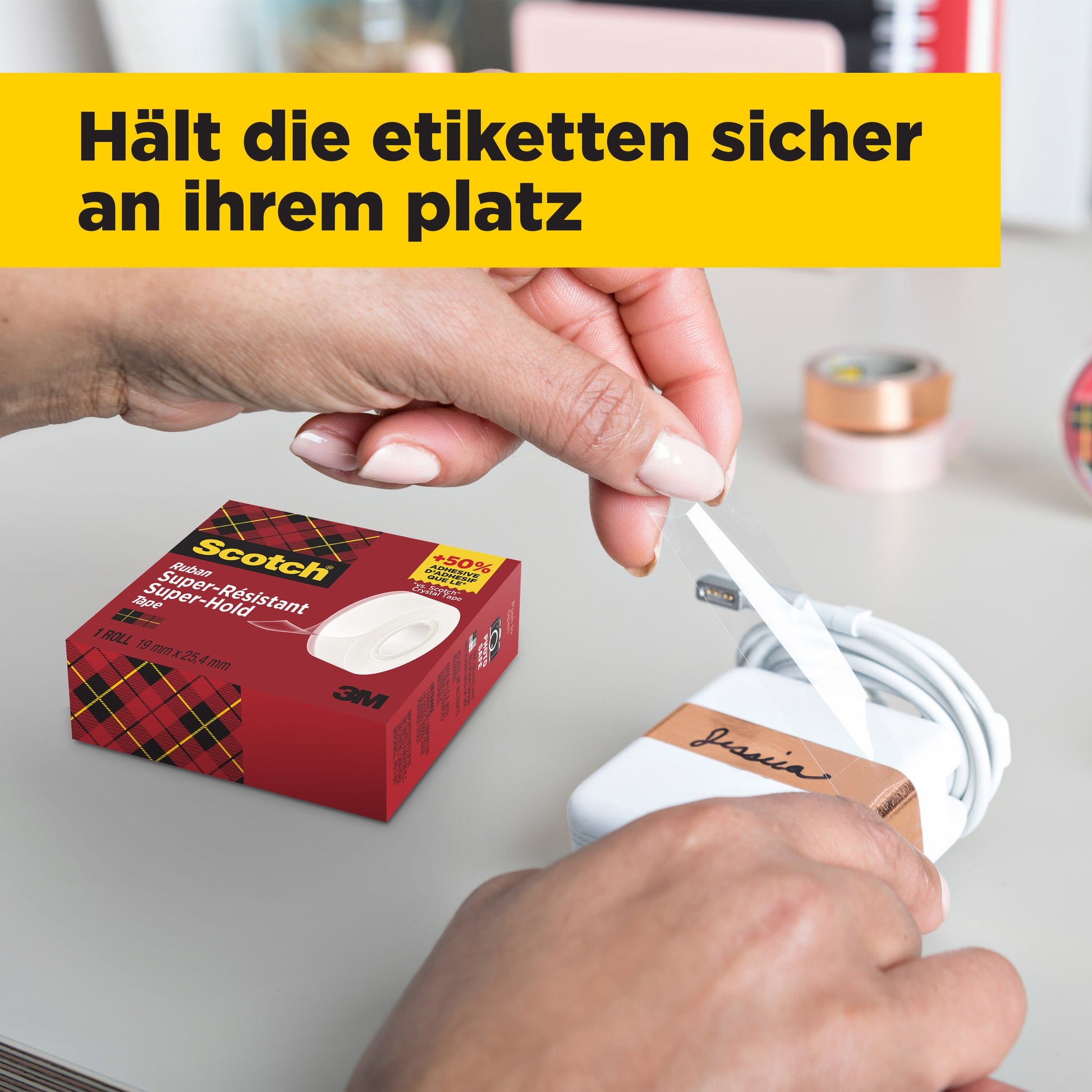 Mit Scotch® Super-Hold Secure Tape (1 Rolle, 19 mm x 25,4 m) von 3M Deutschland GmbH klebt eine Person ein "Louis"-Etikett auf ein weißes Ladegerät. Der deutsche Text lautet: "Hält die Etiketten sicher an ihrem Platz.