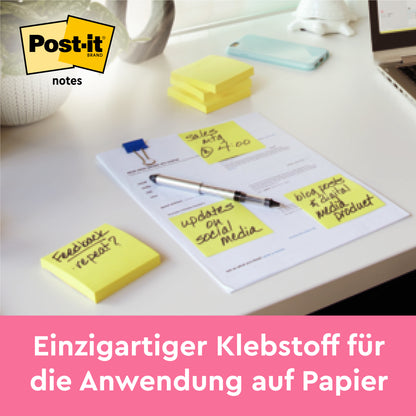 Auf dem Schreibtisch liegen Post-it® Notes in Gelb (76 mm x 127 mm, 100 Blatt/Block), plus extra gestapelte Blöcke. Perfekt für Bürobedarf und Notizen - einzigartiger Klebstoff von 3M Deutschland GmbH. Im Pack: 16 Blöcke + 4 gratis, PEFC-zertifiziert.