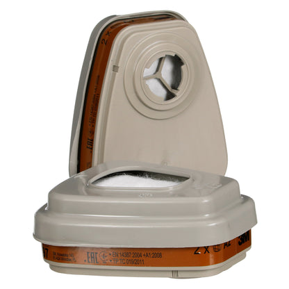 Abgebildet sind zwei beigefarbene, rechteckige 3M™ Filtersatz 6002-1SP A2P2 Filter der 3M Deutschland GmbH - einer aufrecht, einer flach - mit weißem Kreis in der Mitte und brauner Beschriftung am Boden. Die Packung enthält 2x6055, 2x5925, und 2x501.