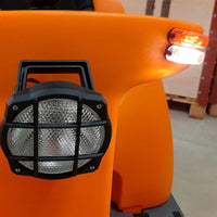 Close-up of a Balimat road set from Diversey Deutschland GmbH & Co. OHG, featuring a round headlight with a black grille and side lights, ready for road use in a warehouse with pallets; suitable for upgrading the Balimat 6500/6500HD.