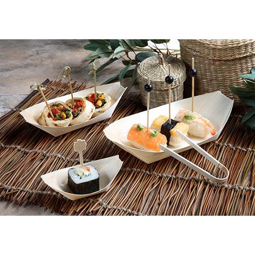 Finger food sushi and appetizers are served in PAPSTAR 50 finger food trays, wooden "pure" "boats" from PAPSTAR GmbH, each piece on a decorative skewer and arranged on bamboo placemats with green leaves and woven baskets in the background.