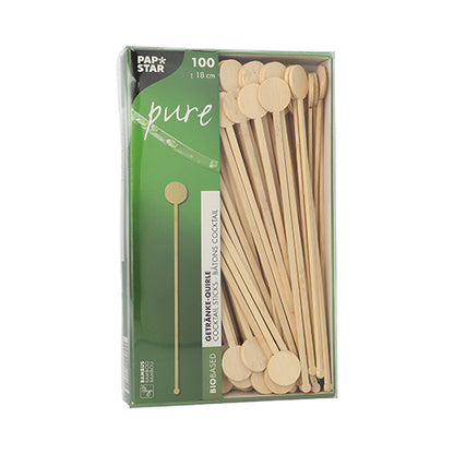 Une boîte avec 100 PAPSTAR GmbH « pur » mélangeurs de boissons en bambou, biodégradables, avec des extrémités rondes et plates, partiellement visibles à travers une fenêtre dans un emballage vert et blanc PAPSTAR Pure.
