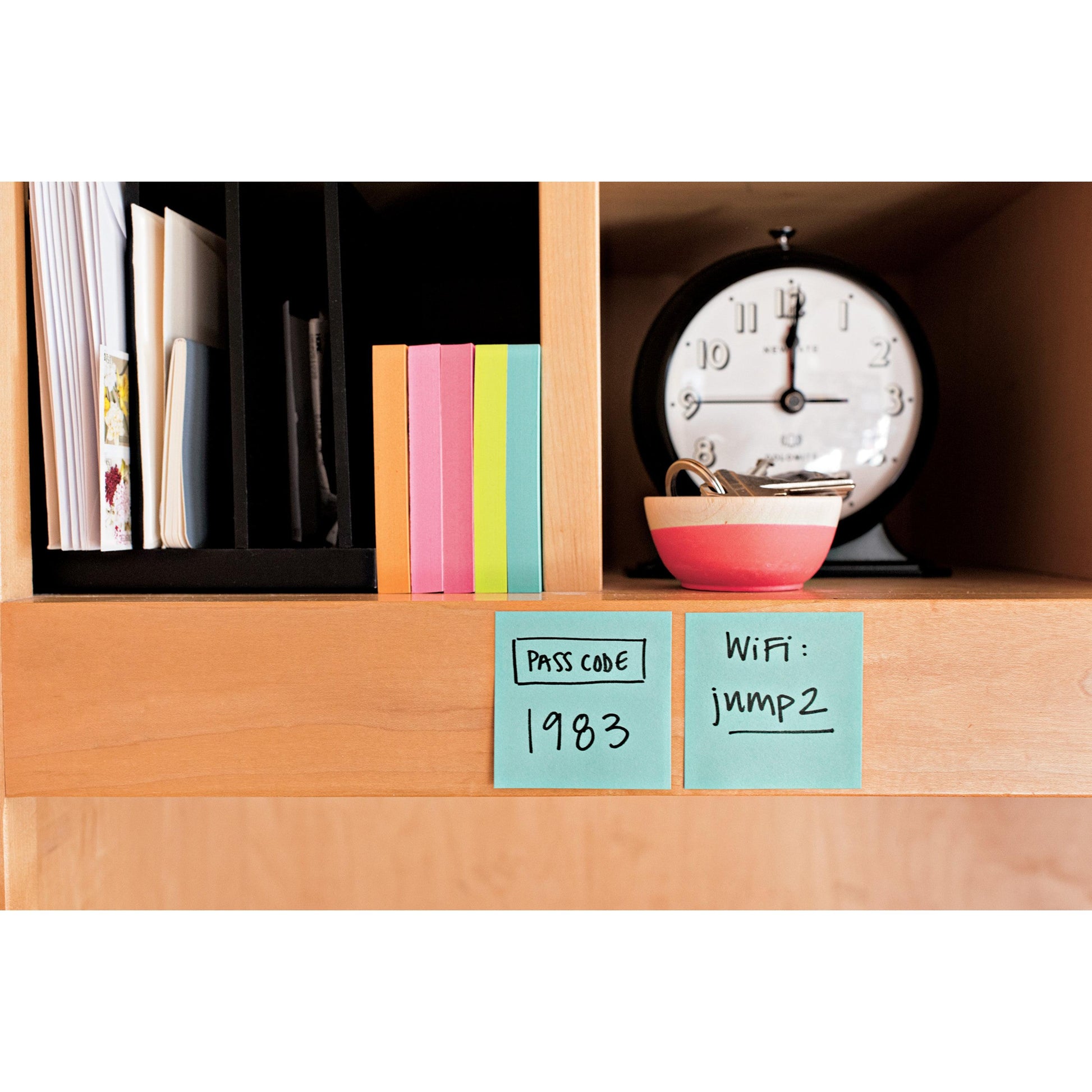 Ein Holzregal mit bunten 3M Post-it® Notes Würfeln (76x76 mm, 450 Blatt), einer Uhr, einer gestreiften Schale mit Schlüsseln und zwei Haftnotizen mit dem Passcode "1983" und dem WiFi-Passwort "jimp2".