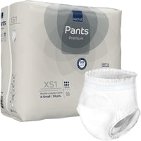 La photo représente un paquet de 24 couches-culottes ABENA Pants XS1, Premium, de la marque Abena Re-Seller GmbH (taille X-Small, couches-culottes pour adultes), sur lequel une couche blanche, placée à l'extérieur de l'emballage, porte les informations sur le produit et les symboles correspondants.