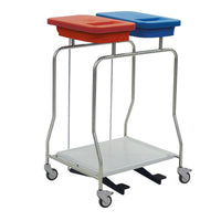 The Novocal "Kompakt" stainless steel dual-compartment waste collector is a stainless steel cart with wheels, two lidded bins—one red and one blue—for waste separation on top, and a flat lower shelf.