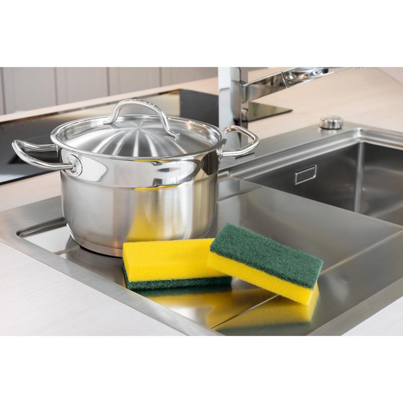 Une casserole en acier inoxydable avec couvercle se trouve à côté de l'évier. À côté, il y a trois éponges, dont une éponge de nettoyage Scotch-Brite® Classic XXL de 3M Deutschland GmbH (6 pièces par paquet). En arrière-plan, on voit un robinet moderne.