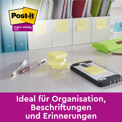 Auf einem Schreibtisch liegen Stifte, ein Telefon, beschriftete Mappen und Post-it® Super Sticky Notes (Gelb, 51 x 76 mm) von 3M Deutschland GmbH. Der deutsche Text lautet: "Ideal für Organisation, Beschriftungen und Erinnerungen.
