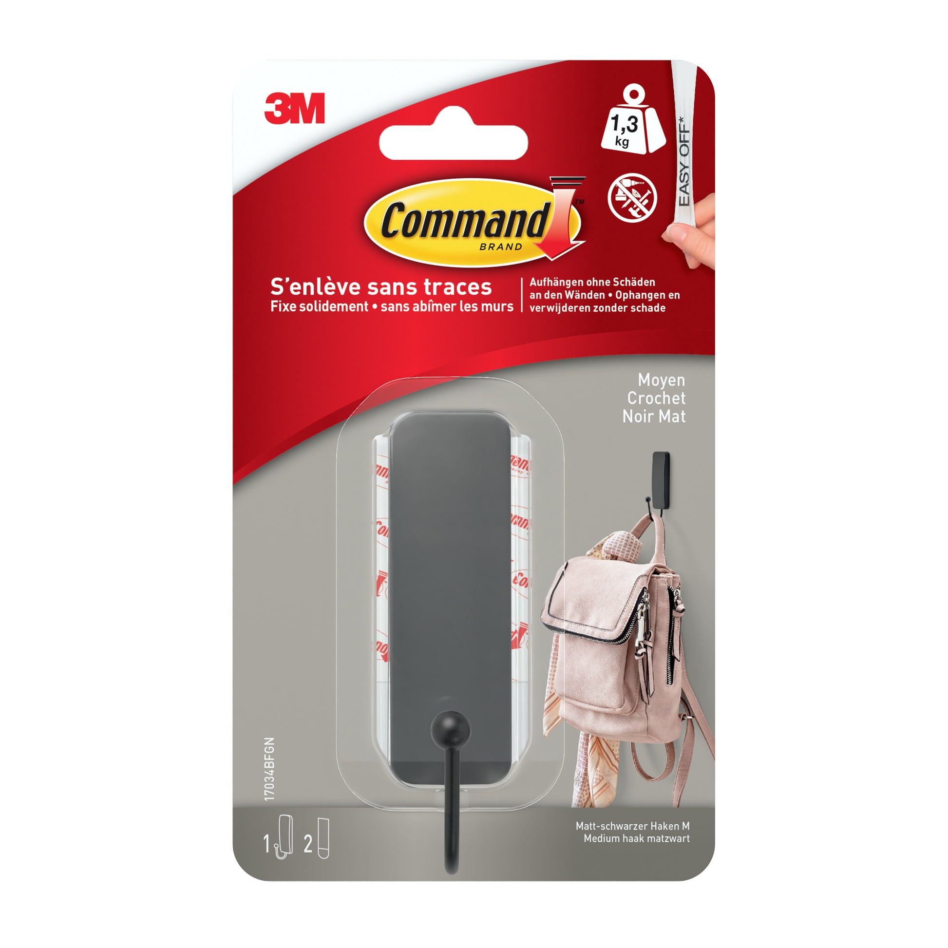 Eine Packung 3M Deutschland GmbH Mittelgroßer Command™ mattschwarzer Haken, 17034B (1 Haken, 2 Streifen), mit roter, weißer und grauer Verpackung mit französischen und deutschen Produktangaben und der Abbildung einer am Haken hängenden Tasche.